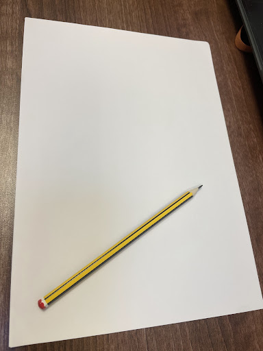 A HB pencil seen resting on a sheet of plain white A4 paper.