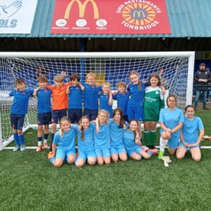 Two Paddock Wood Primary Academy Football teams are pictured standing together with their arms around each other under a goalpost.